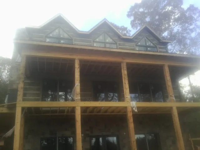 Dormers and porch framing on a large log home under construction — Roof Coating work by our crew in Blanchard